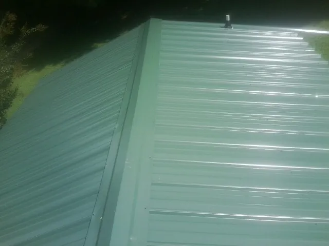 New green metal panels meeting at the ridge of a roof — Flat Roof Repair work by our crew in Vacherie