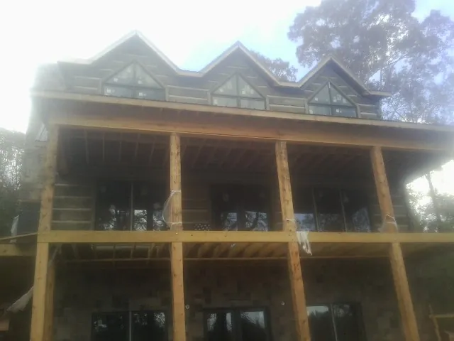 Dormers and porch framing on a large log home under construction — Roof Coating work by our crew in Vacherie