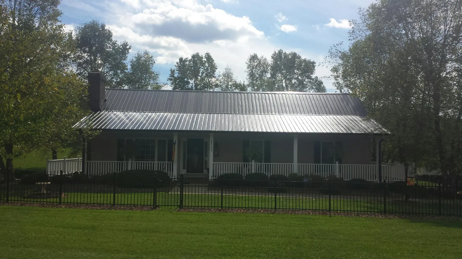 Gray metal roof on a brick ranch with a full width front porch — Gutter Guard Installation work by our crew in Vacherie