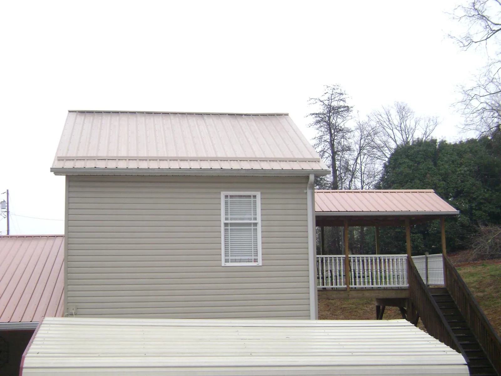 Tan metal roofs on a two story addition and attached porch, from a Roof Replacement job in Vacherie