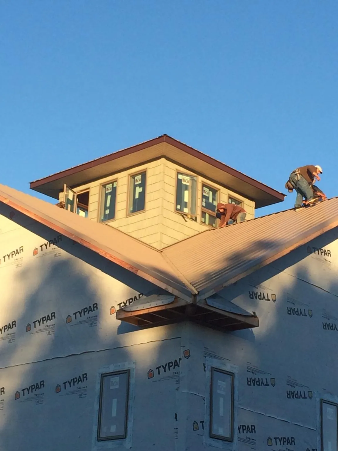 Roofers working around a rooftop cupola on a new metal roof at sunset — Roof Waterproofing in Vacherie by Roofing Brothers